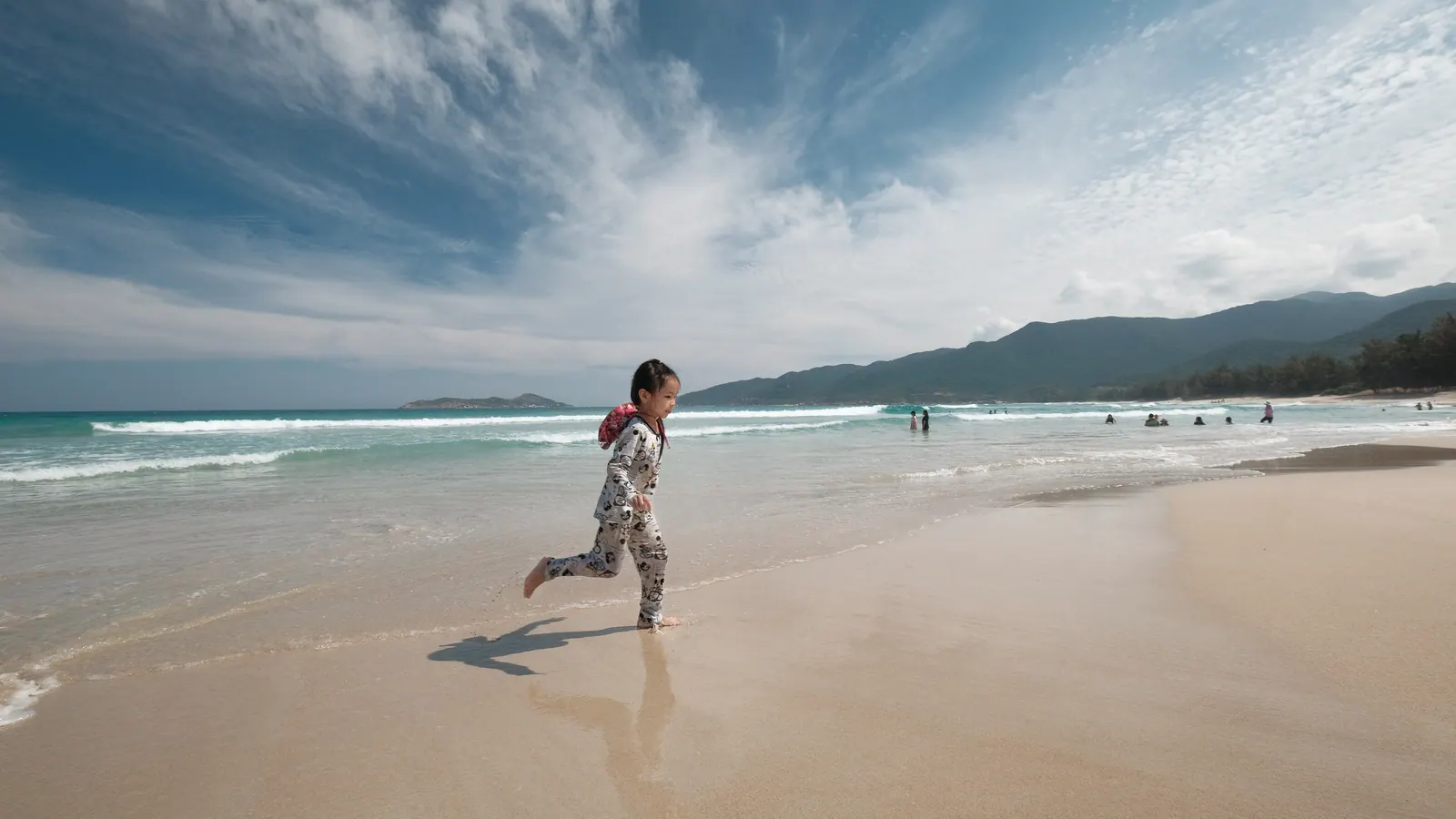 A girl running on the wide empty sand of Cam Ranh beach.